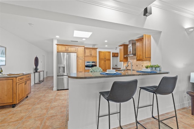 715 45th Ave NE, Saint Petersburg, FL 33703 - kitchen featuring stainless steel appliances, wall chimney range hood, a skylight, a peninsula, and ornamental molding