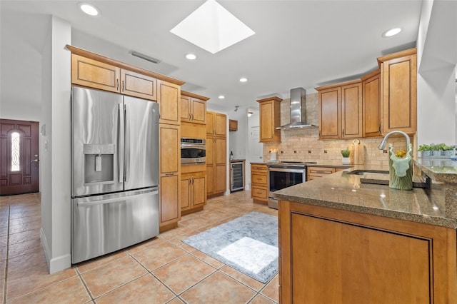 715 45th Ave NE, Saint Petersburg, FL 33703 - kitchen featuring stainless steel appliances, wall chimney exhaust hood, a skylight, dark stone counters, and backsplash