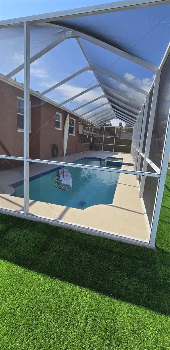 1102 Goshen Rd, Tarpon Springs, FL 34689 - view of swimming pool with glass enclosure, a patio area, a pool with connected hot tub, and a yard
