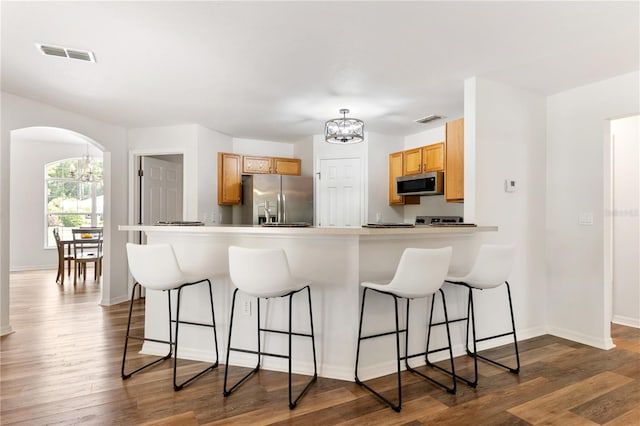 9700 SW 196th Cir, Dunnellon, FL 34432 - kitchen with stainless steel appliances, arched walkways, a chandelier, a kitchen bar, and dark wood finished floors