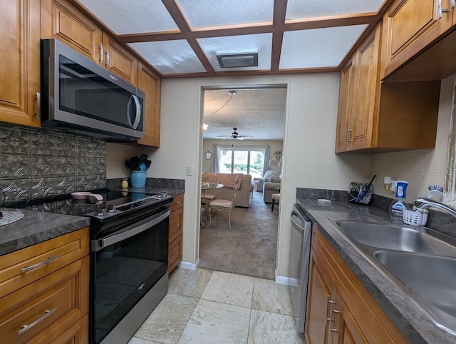 8765 Bardmoor Blvd Unit 108, Seminole, FL 33777 - kitchen featuring stainless steel appliances, a sink, dark countertops, brown cabinets, and a textured ceiling