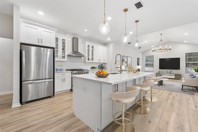 9402 Woodbay Dr, Tampa, FL 33626 - kitchen with appliances with stainless steel finishes, wall chimney range hood, a sink, light wood finished floors, and white cabinetry
