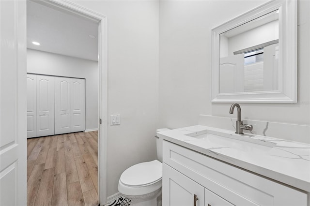 9402 Woodbay Dr, Tampa, FL 33626 - half bathroom with vanity, toilet, wood finished floors, baseboards, and recessed lighting