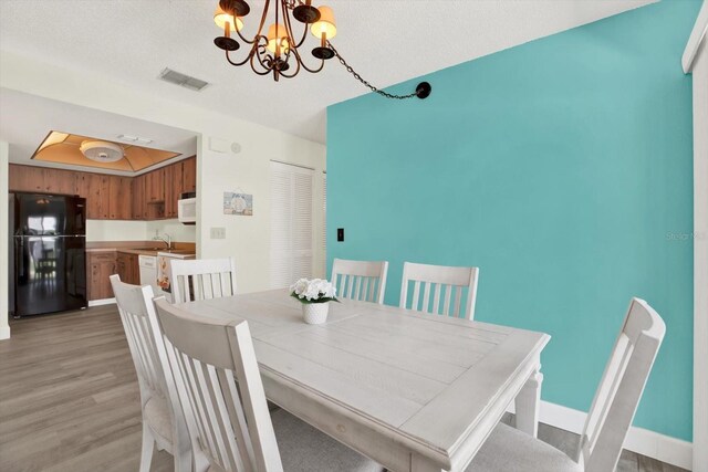 3146 37th Ln S Unit A, Saint Petersburg, FL 33711 - dining space featuring a chandelier, light wood-type flooring, baseboards, and a textured ceiling