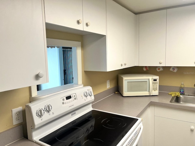 880 Mandalay Ave Unit C1103, Clearwater Beach, FL 33767 - kitchen with white appliances, a sink, white cabinets, and light countertops