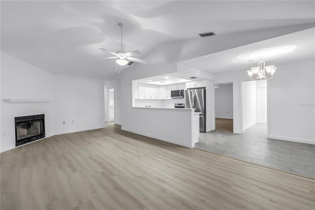 13898 Egret Ln, Clearwater, FL 33762 - unfurnished living room featuring vaulted ceiling, a fireplace, light wood-type flooring, baseboards, and a chandelier