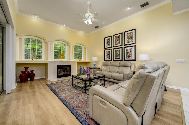 8444 Shenandoah Run, Wesley Chapel, FL 33544 - living room featuring ceiling fan, baseboards, a fireplace with flush hearth, light wood-type flooring, and ornamental molding