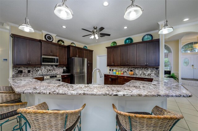8444 Shenandoah Run, Wesley Chapel, FL 33544 - kitchen with appliances with stainless steel finishes, ceiling fan, light tile patterned floors, decorative backsplash, and a breakfast bar area