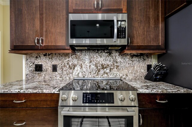 8444 Shenandoah Run, Wesley Chapel, FL 33544 - kitchen featuring appliances with stainless steel finishes, dark brown cabinetry, tasteful backsplash, and light stone counters