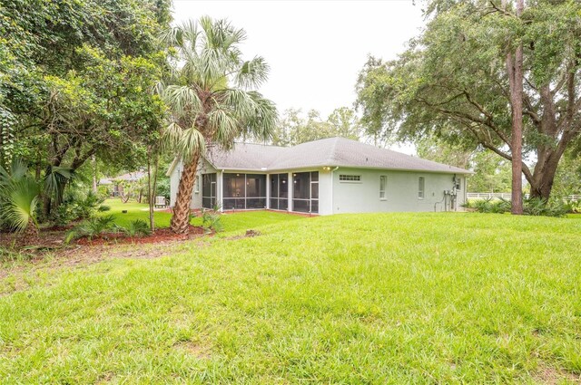 8444 Shenandoah Run, Wesley Chapel, FL 33544 - rear view of house with a sunroom, a lawn, and stucco siding