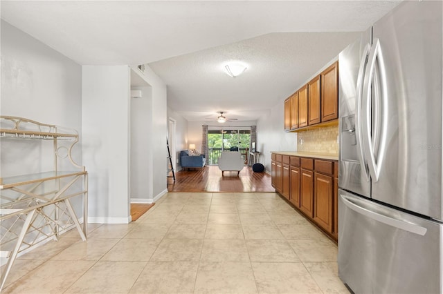 1028 Apollo Beach Blvd Unit 203, Apollo Beach, FL 33572 - kitchen featuring stainless steel fridge, brown cabinetry, light tile patterned floors, backsplash, and light countertops
