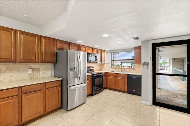 1028 Apollo Beach Blvd Unit 203, Apollo Beach, FL 33572 - kitchen with black appliances, a textured ceiling, brown cabinetry, light countertops, and tasteful backsplash