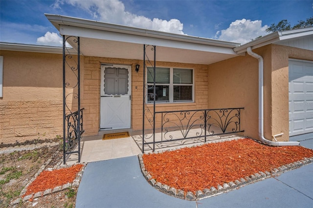 9100 Lunar Ln, Port Richey, FL 34668 - view of exterior entry with stucco siding, covered porch, and an attached garage