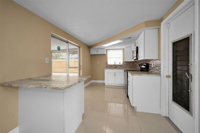 9100 Lunar Ln, Port Richey, FL 34668 - kitchen featuring stainless steel appliances, decorative backsplash, white cabinetry, baseboards, and a peninsula