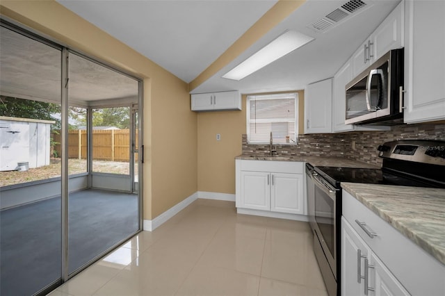 9100 Lunar Ln, Port Richey, FL 34668 - kitchen with stainless steel appliances, a sink, decorative backsplash, white cabinetry, and light stone countertops