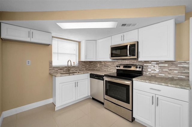 9100 Lunar Ln, Port Richey, FL 34668 - kitchen with stainless steel appliances, backsplash, white cabinetry, baseboards, and a sink