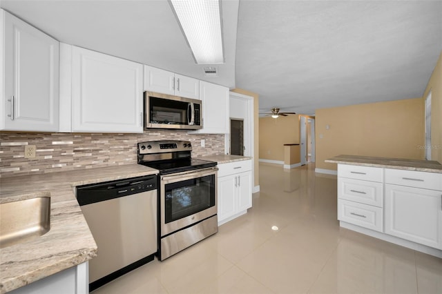 9100 Lunar Ln, Port Richey, FL 34668 - kitchen with appliances with stainless steel finishes, backsplash, white cabinets, light countertops, and light tile patterned floors