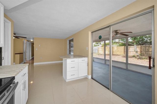 9100 Lunar Ln, Port Richey, FL 34668 - kitchen with ceiling fan, white cabinets, light tile patterned floors, and electric stove