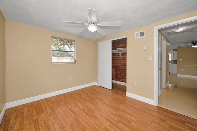 9100 Lunar Ln, Port Richey, FL 34668 - unfurnished bedroom featuring light wood-style floors, a closet, baseboards, and a ceiling fan