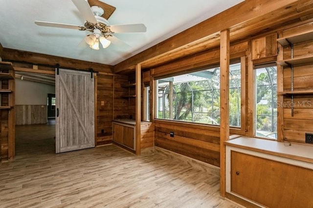 2035 Nolan Dr, Dunedin, FL 34698 - spare room featuring wooden walls, a barn door, wood finished floors, and ceiling fan