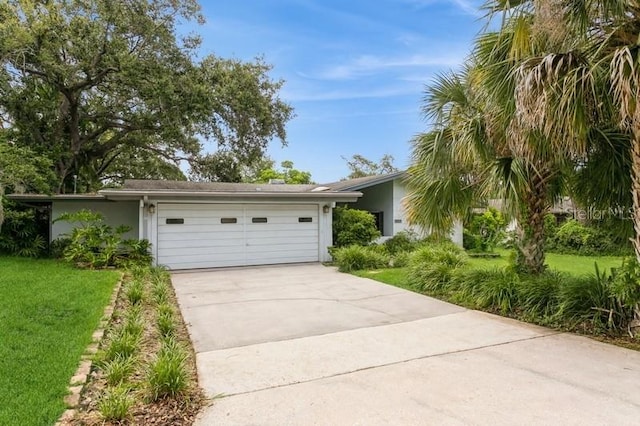 2035 Nolan Dr, Dunedin, FL 34698 - view of front of house with concrete driveway, a garage, stucco siding, and a front lawn