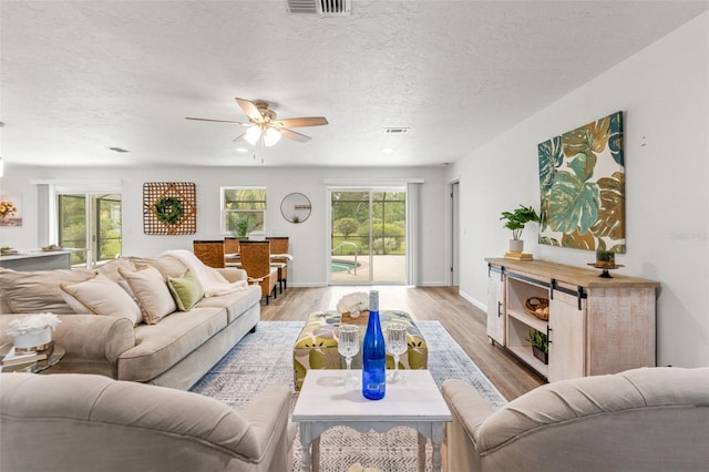 3956 N Tamarisk Pt, Beverly Hills, FL 34465 - living room with ceiling fan, light wood-type flooring, a textured ceiling, and baseboards