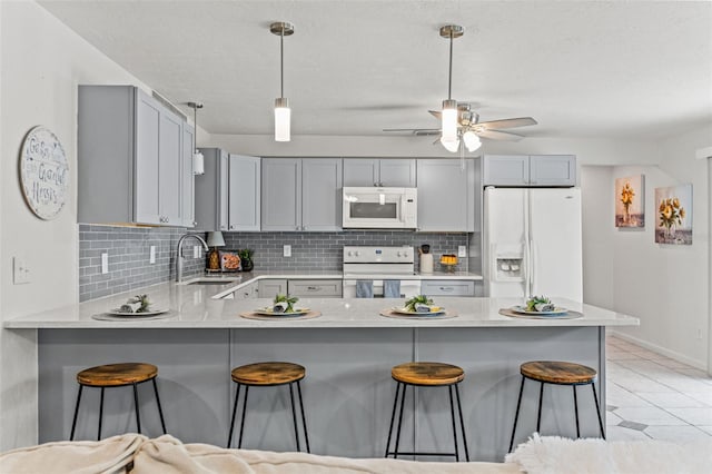 3956 N Tamarisk Pt, Beverly Hills, FL 34465 - kitchen with white appliances, a sink, a peninsula, backsplash, and a breakfast bar