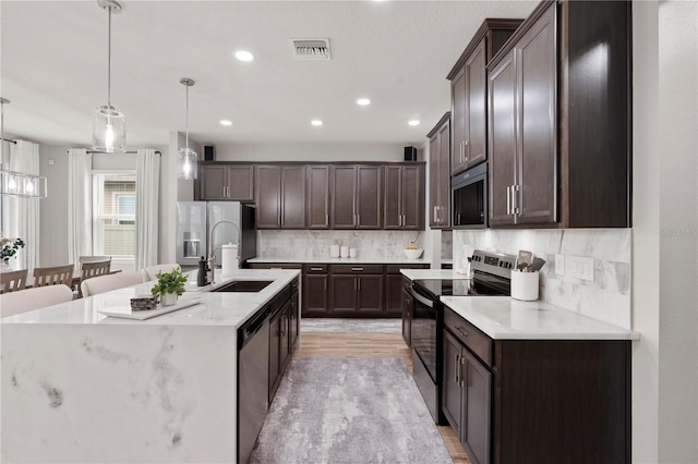 11719 Tetrafin Dr, Riverview, FL 33579 - kitchen featuring stainless steel appliances, a sink, dark brown cabinetry, backsplash, and hanging light fixtures