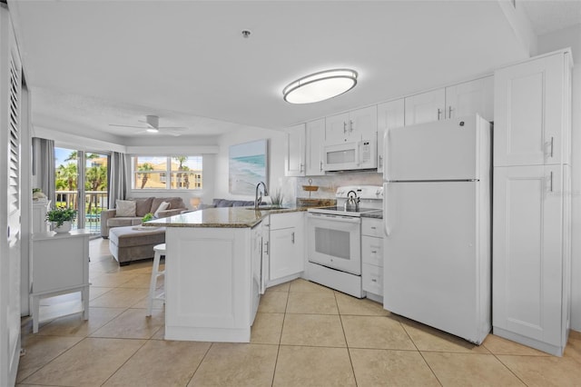5445 Gulf Blvd Unit 210, St Pete Beach, FL 33706 - kitchen with white appliances, a sink, a peninsula, and white cabinetry