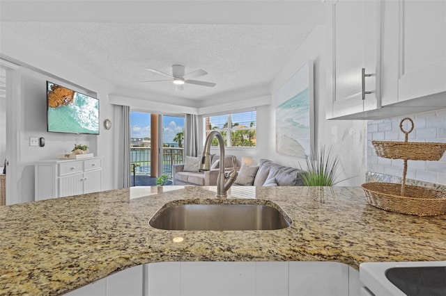 5445 Gulf Blvd Unit 210, St Pete Beach, FL 33706 - kitchen featuring a sink, light stone countertops, ceiling fan, tasteful backsplash, and open floor plan