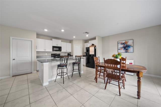 4403 Eternal Prince, Sun City Center, FL 33573 - kitchen featuring black appliances, white cabinets, baseboards, a kitchen island, and a breakfast bar