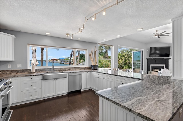 511 Island Way, Clearwater Beach, FL 33767 - kitchen with appliances with stainless steel finishes, a textured ceiling, dark stone countertops, ceiling fan, and dark wood-style floors