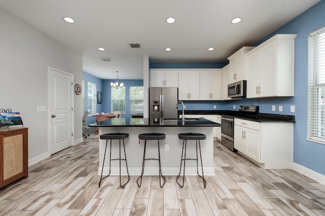 4301 5th Ave N, Saint Petersburg, FL 33713 - kitchen with appliances with stainless steel finishes, dark countertops, a sink, a chandelier, and light wood-style flooring