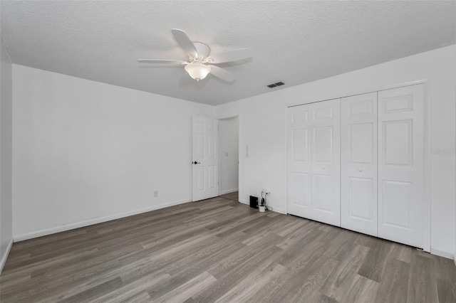 2063 Ridgecrest Dr, Dunedin, FL 34698 - unfurnished bedroom with wood finished floors, a textured ceiling, a closet, baseboards, and ceiling fan