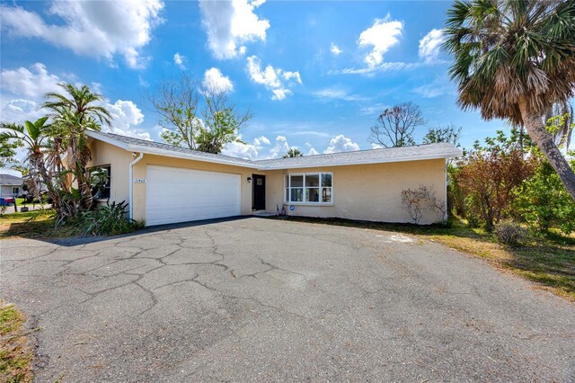 11465 7th St E, Treasure Island, FL 33706 - view of front facade with an attached garage, asphalt driveway, and stucco siding