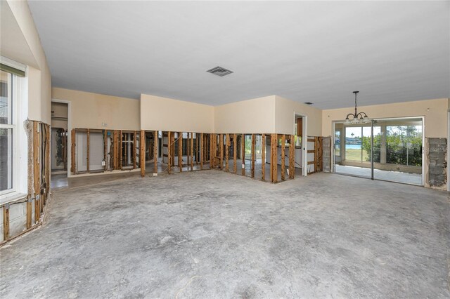 11465 7th St E, Treasure Island, FL 33706 - unfurnished room featuring a chandelier and unfinished concrete flooring