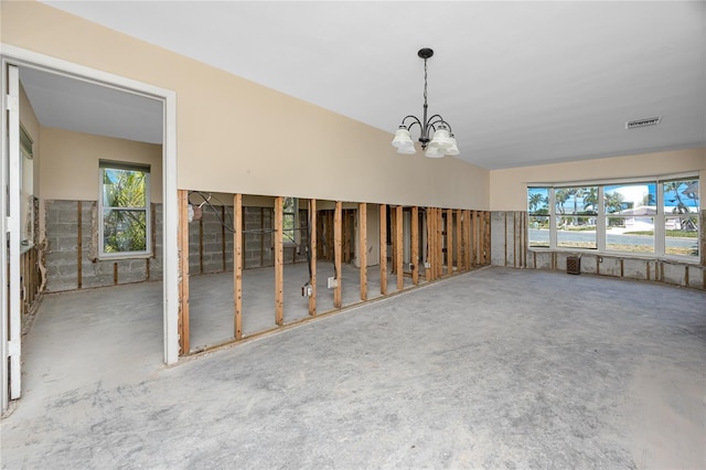 11465 7th St E, Treasure Island, FL 33706 - unfurnished room featuring a chandelier and unfinished concrete floors