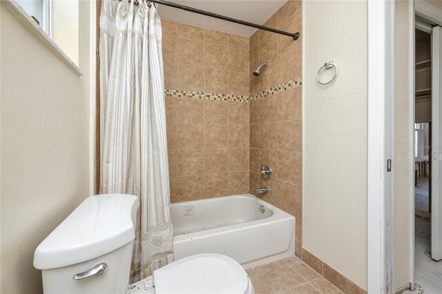 11465 7th St E, Treasure Island, FL 33706 - bathroom featuring toilet, shower / bath combo with shower curtain, tile patterned floors, and baseboards