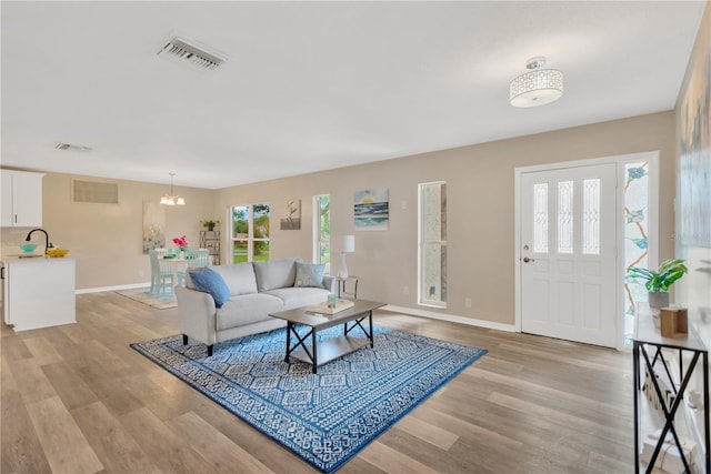 704 Childers Loop, Brandon, FL 33511 - living area featuring baseboards, light wood-style floors, and a chandelier