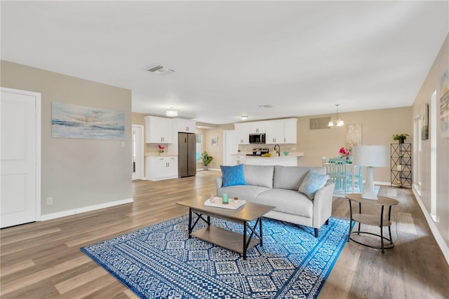 704 Childers Loop, Brandon, FL 33511 - living area featuring light wood-type flooring, baseboards, and a chandelier