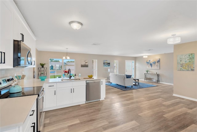 704 Childers Loop, Brandon, FL 33511 - kitchen featuring stainless steel appliances, a sink, a peninsula, open floor plan, and light wood-type flooring
