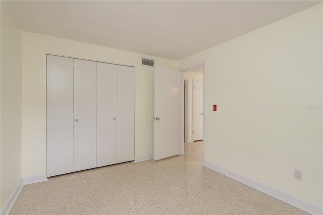 2020 Douglas Ave, Dunedin, FL 34698 - unfurnished bedroom with baseboards, dark aggregate flooring, and a closet