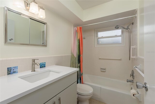 2020 Douglas Ave, Dunedin, FL 34698 - bathroom featuring tile walls, toilet, shower / tub combo with curtain, vanity, and a wainscoted wall