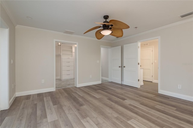 12 Bayou Ln, Palm Harbor, FL 34683 - unfurnished bedroom with crown molding, light wood finished floors, a walk in closet, and a ceiling fan