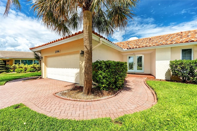 2096 Massachusetts Ave NE, Saint Petersburg, FL 33703 - view of side of home featuring french doors, a garage, stucco siding, and decorative driveway