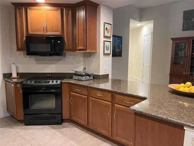 12064 Navale Ln, Orlando, FL 32827 - kitchen with black appliances, dark stone countertops, light tile patterned floors, and brown cabinetry