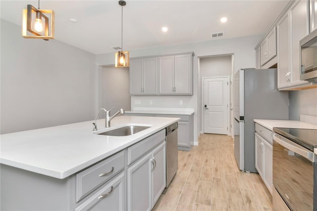 4262 Cloud Hopper Way, Lutz, FL 33559 - kitchen with stainless steel appliances, gray cabinetry, light countertops, an island with sink, and recessed lighting