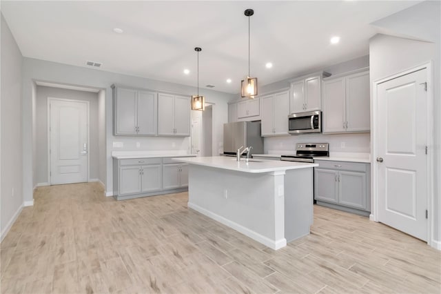 4262 Cloud Hopper Way, Lutz, FL 33559 - kitchen with appliances with stainless steel finishes, gray cabinets, light wood-style flooring, light countertops, and a kitchen island with sink