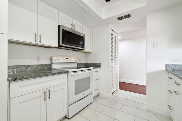 13612 S Village Dr Unit 5201, Tampa, FL 33618 - kitchen featuring electric range, stainless steel microwave, dark stone counters, white cabinetry, and baseboards