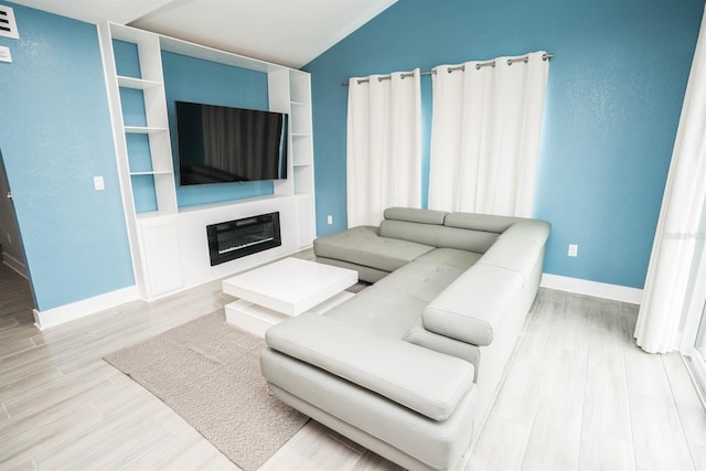 5712 Biscayne Ct Unit 201, New Port Richey, FL 34652 - living area featuring vaulted ceiling, wood finished floors, baseboards, and a glass covered fireplace